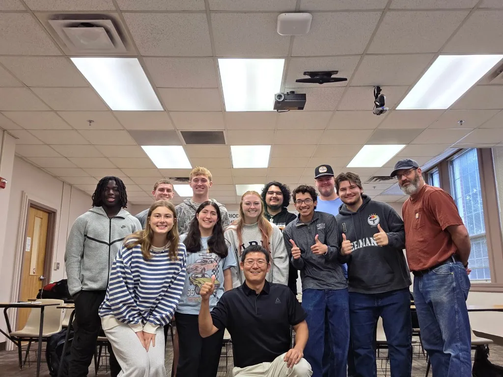 Dr. Wei with students after class, several giving a thumbs-up.