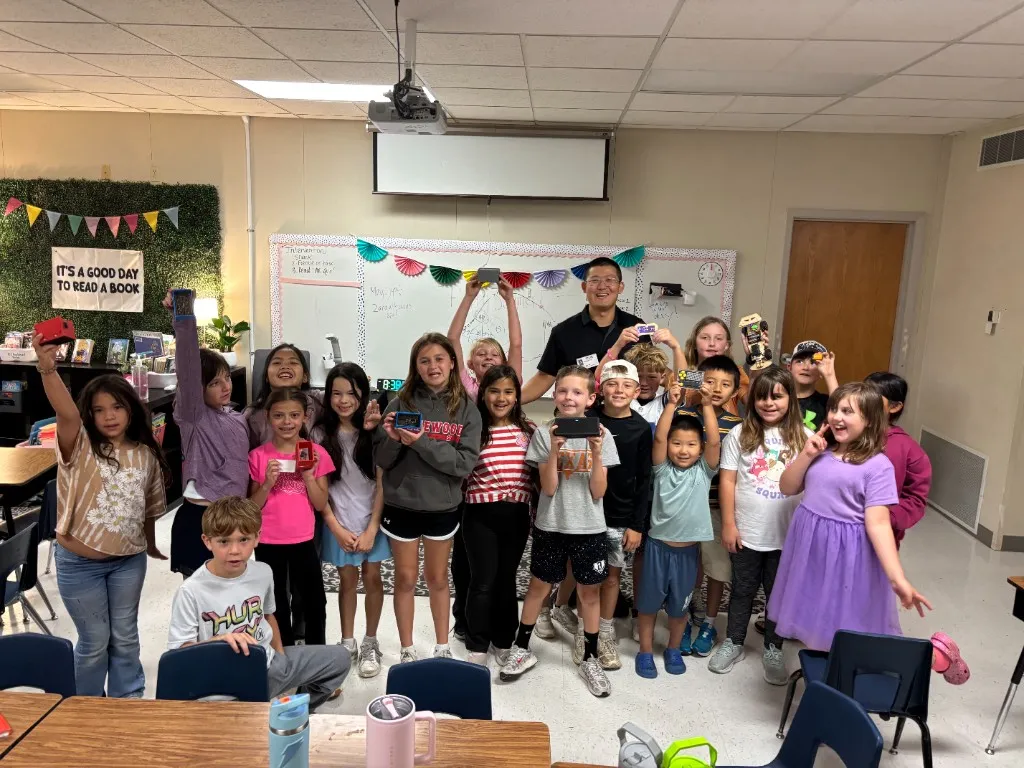 Dr. Wei volunteering with elementary students and their electronics projects.